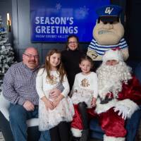 Parents with two girls on Santa's lap smile with Louie standing